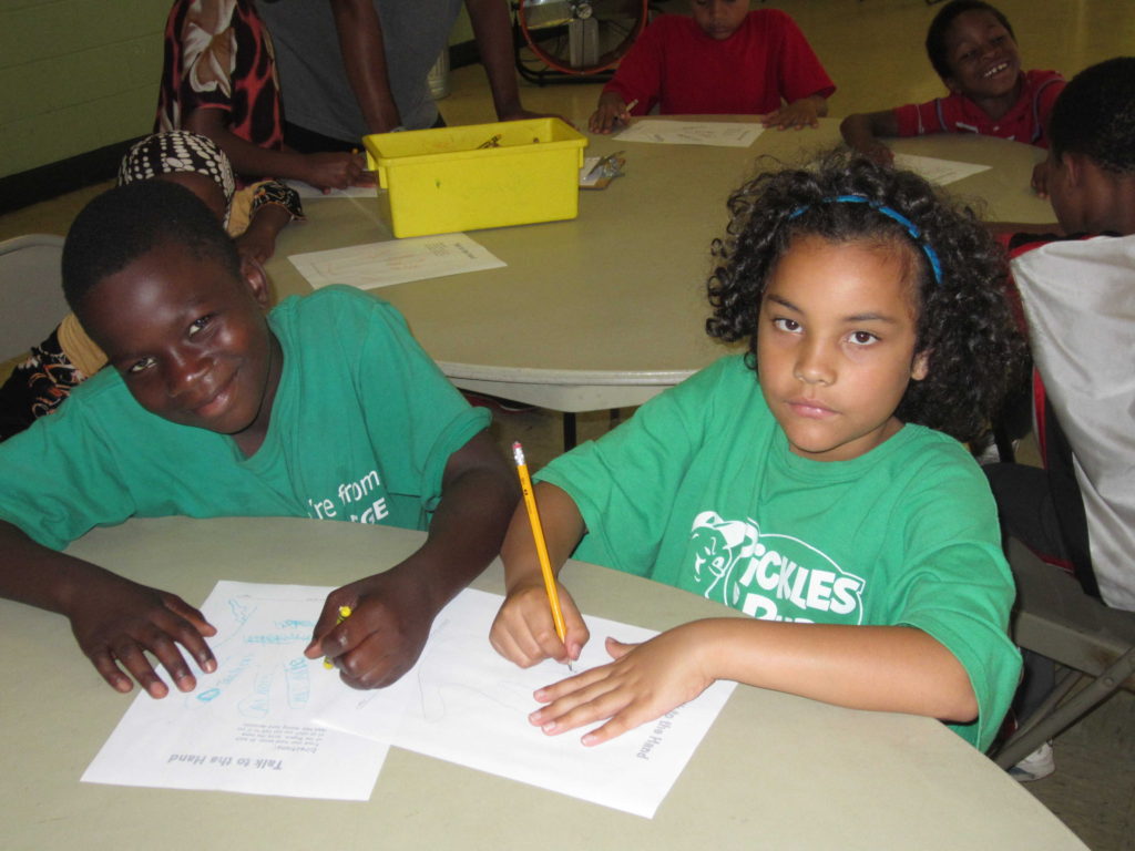 Abdi Adan, 13, and Dianyarett Quinones, 9, trace their hands, filling in each digit with the name of a trusted adult, as part of the anti-gang program at Riverview Apartments.