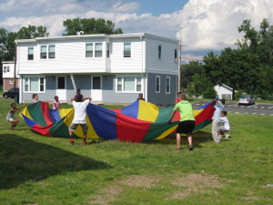 Children hoist a brightly colored parachute into the air at Robinson Gardens Apartments.