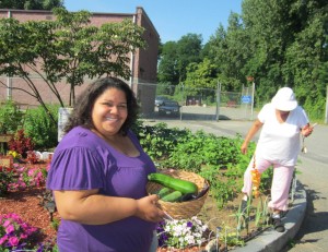 Jennie Lane Tenants' Association President Jessica Quiñonez holds a basket of plenty at the garden next to the development's Community Room.