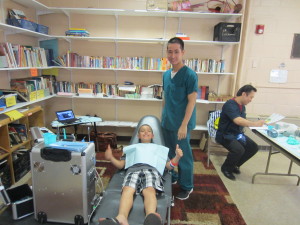 Melquisedec Santiago, 8, gets a teeth-cleaning at the Commonwealth Mobile Oral Health Services clinic set up for the day at Sullivan. Standing next to him is dental assistant Trung Nguyen. Seated at the table behind them is Dr. Qui Nguyen.