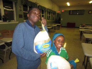 Shoeb Adan, 12, and Yasmin Abdi, 9, hold their turkeys at Riverview Apartments Community Room.