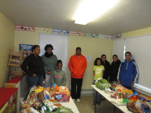 Sincia Perrin and her family, at left, and Maria Ortiz and her daughters, at right, look at the Christmas dinner given by an anonymous donor. SHA Youth Engagement Coordinator Jimmie Mitchell is in the center.