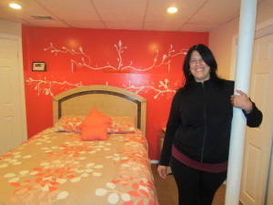 Elizabeth Rodriguez stands in the bedroom of her new home in Springfield. The back wall was painted by her son Mac Millan and his fellow graphic arts students at Springfield Technical Community College.