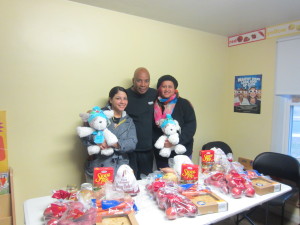 Robinson Gardens resident Yahaira Ortiz, Youth Engagement Coordinator Jimmie Mitchell and Mariela Caraballo stand before the holiday dinners given to residents by Santino Tomassini.