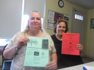 Robinson Gardens Apartments residents Petra Menger and Ivette Fernandez hold copies of their community garden newsletter.